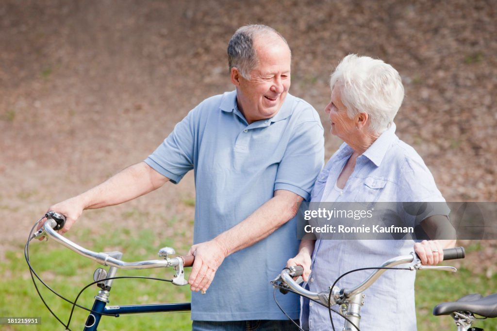 Caucasian couple walking bicycles together