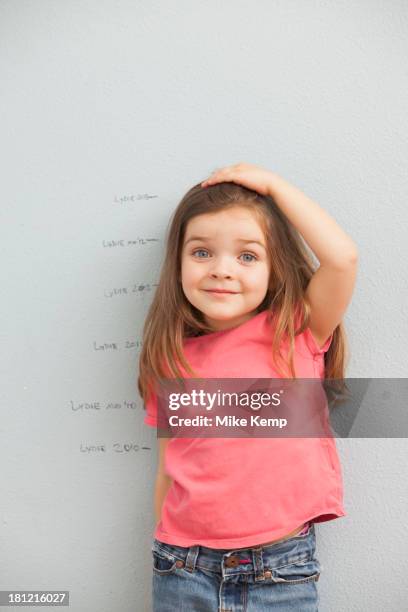 caucasian girl measuring her height on wall - child's wall height stock-fotos und bilder