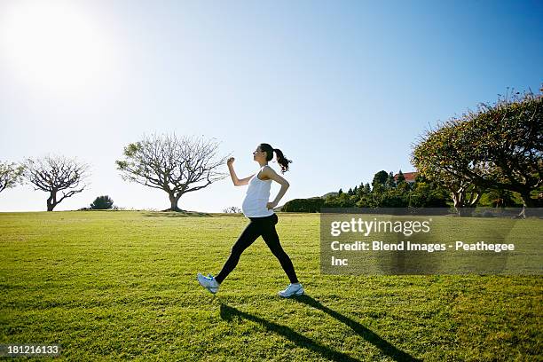 Pregnant mixed race woman exercising in field