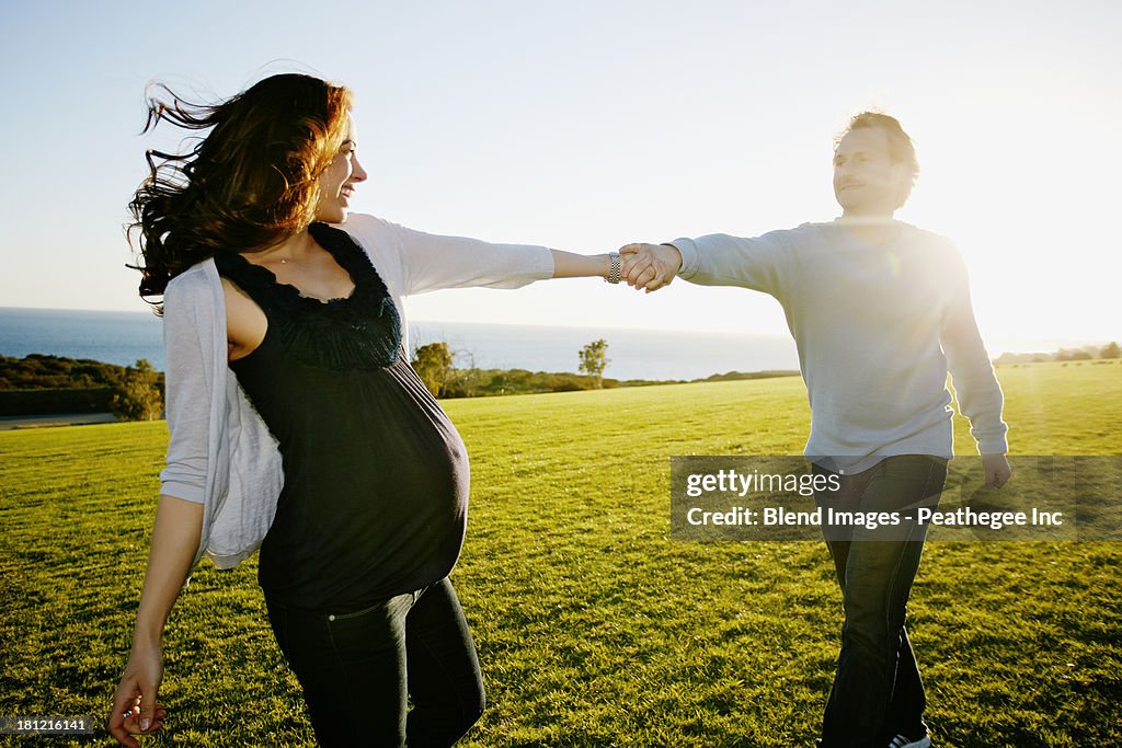 Pregnant couple playing in field