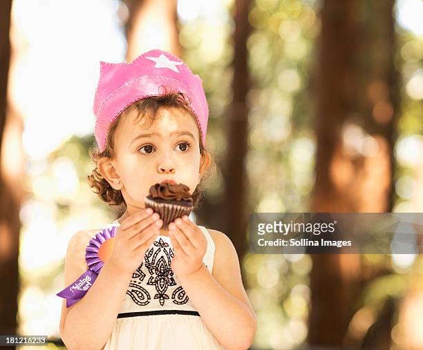 hispanic girl eating cupcake outdoors - cupcakes girls fotografías e imágenes de stock