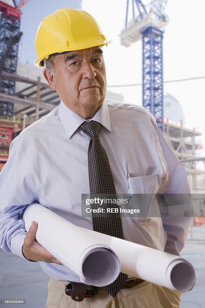 Hispanic businessman carrying blueprints