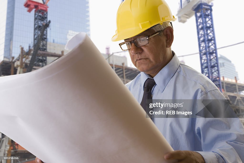 Hispanic businessman reading blueprints