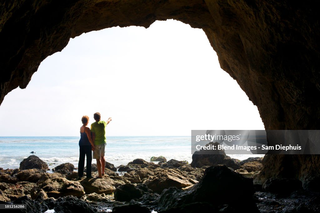 Couple standing in rocky beach cave