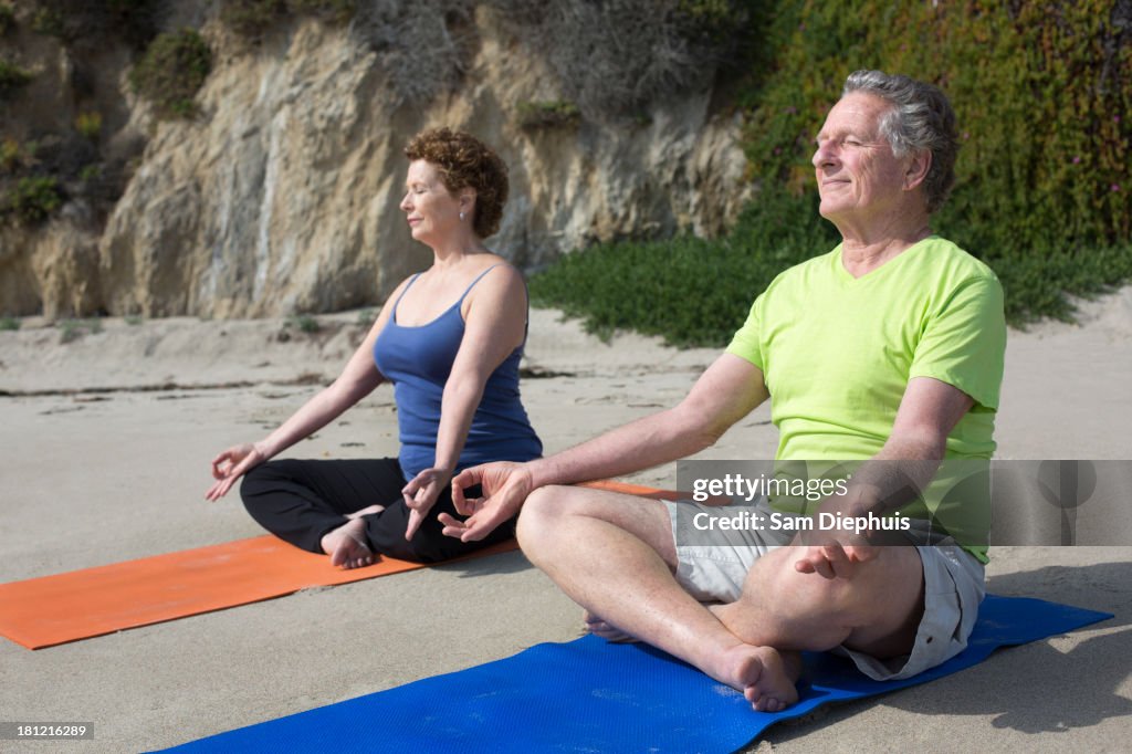 Caucasian couple meditating on beach