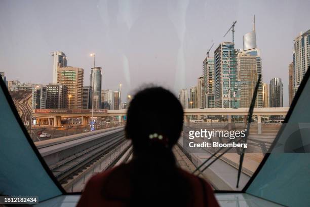 Passenger looks out towards the city skyline from onboard a metro train in Dubai, United Arab Emirates, on Wednesday, Nov. 29, 2023. More than 70,000...
