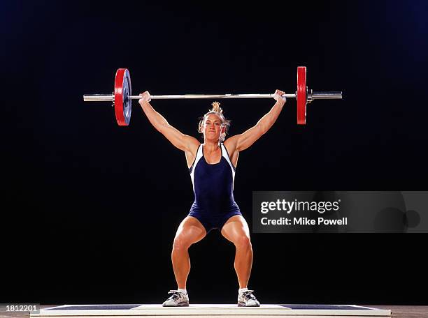 Model Released/Property Released: Competitive female weightlifter raising barbell over head