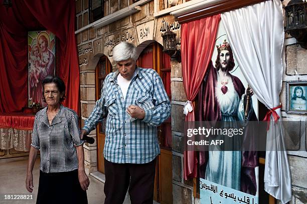 Johny, a Syrian Christian, assists a disabled elderly woman in the courtyard of Mar Elias House, a church hostel for the indigent in the old City of...