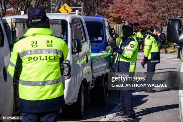 Policemen stand guard next to trucks containing caged dogs during a protest by dog farmers against the government's move to ban dog meat consumption,...