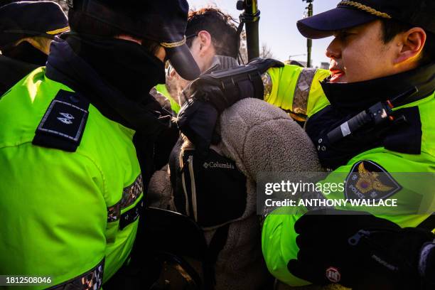 Police detain a protester during a protest against the government's move to ban dog meat consumption, in Seoul on November 30, 2023. Hundreds of...