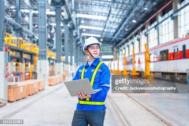 a cheerful young engineer is pictured in a railway workshop. - maschinenbau stock-fotos und bilder