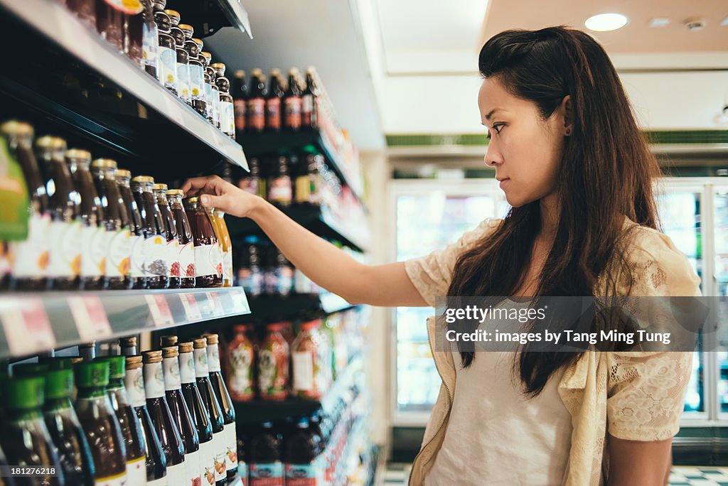 Young lady looking at labels on drinks in a store