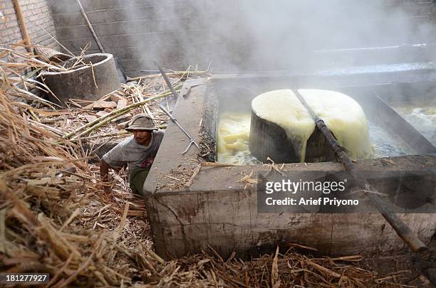 Worker supervising cooking stoves of boiling sugar cane juice while making brown sugar in a small factory in Slumbung village. Most Indonesian people...