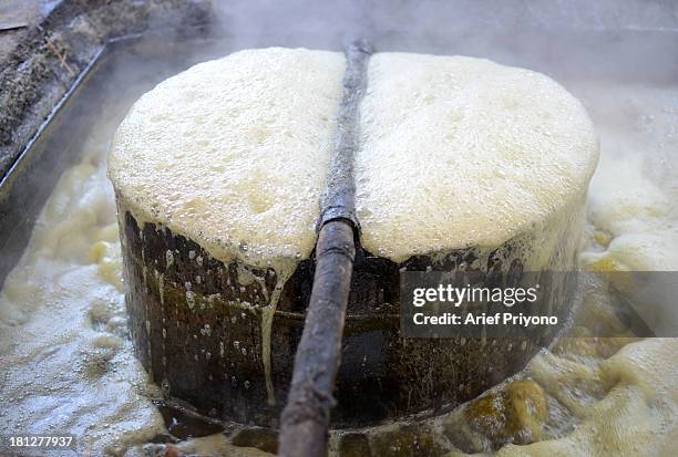 The cooking process, with boiling vats of sugar cane juice, while making brown sugar in a small factory in Slumbung village. Most Indonesian people...