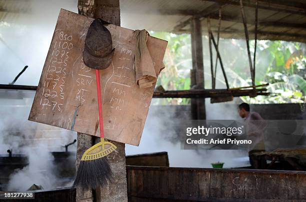 Worker supervising boiling vats of sugar cane juice while making brown sugar in a small factory in Slumbung village. Most Indonesian people use brown...