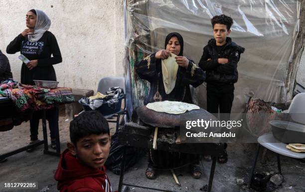 Woman, displaced from her home as a result of the Israeli attacks, makes preparation to cook a meal with the clay oven, Palestinians produced with...