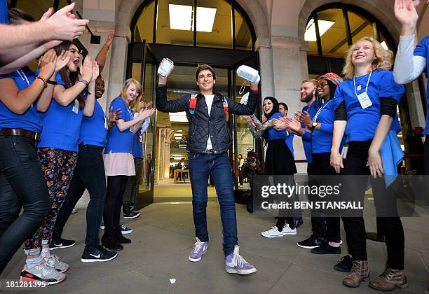 Jesse Green from London gestures as he leaves with his iPhone 5S after being the second person to enter the Apple store after they went on sale in...