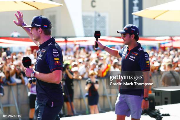 Max Verstappen of the Netherlands and Oracle Red Bull Racing and Sergio Perez of Mexico and Oracle Red Bull Racing wave to the crowd from the fan...