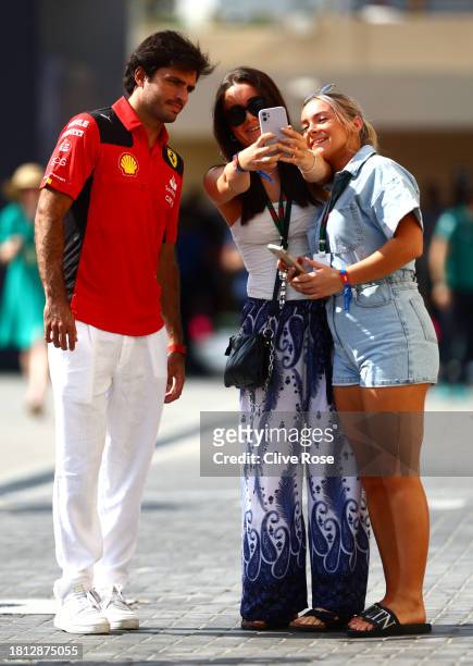 Carlos Sainz of Spain and Ferrari poses for a selfie with a fan in the Paddock prior to final practice ahead of the F1 Grand Prix of Abu Dhabi at Yas...