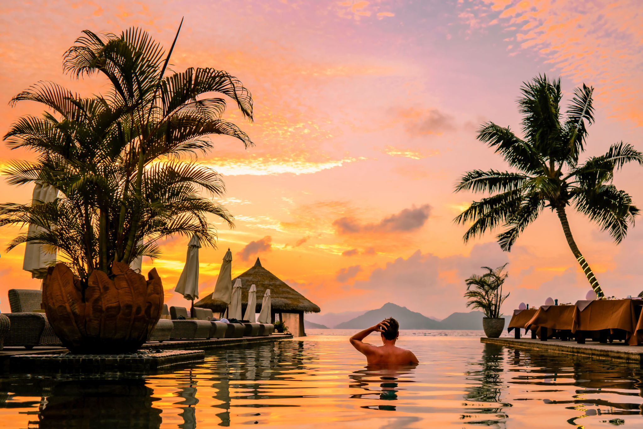 young men in swimming pool during sunset, Luxury swimming pool in tropical resort in the Seychelles young men in swimming pool during sunset, Luxury swimming pool in tropical resort in the Seychelles