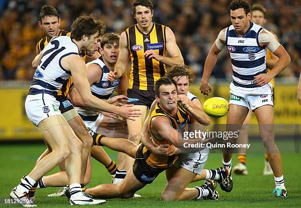 Brian Lake of the Hawks handballs whilst being tackled by Mitch Duncan of the Cats during the AFL First Preliminary FInal match between the Hawthorn...
