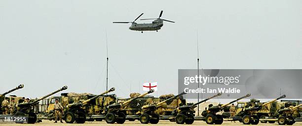 British Chinook helicopter flies over cannons at Camp Gibraltar February 24, 2003 near Kuwait City, Kuwait. British Defense Secretary Geoff Hoon is...