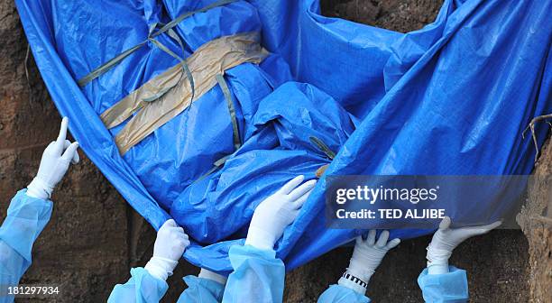 Volunteers help lower down the body of a suspected Muslim rebel killed in the stand-off between Philippine government forces and members of Moro...