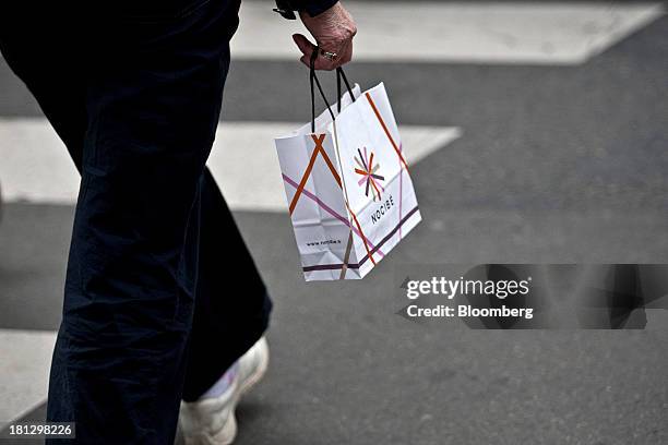 Customer carries a Nocibe SA paper bag after shopping at the company's beauty store in Paris, France, on Thursday, Sept. 19, 2013. Bank of France...