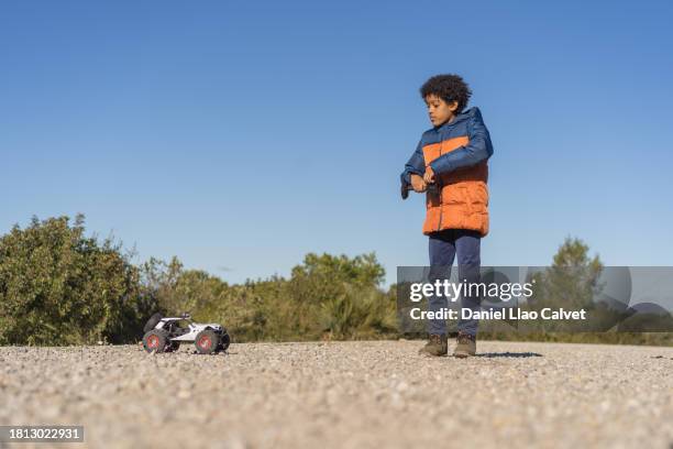 african american boy playing with a radio controlled toy car outdoors. - remote control car stock pictures, royalty-free photos & images