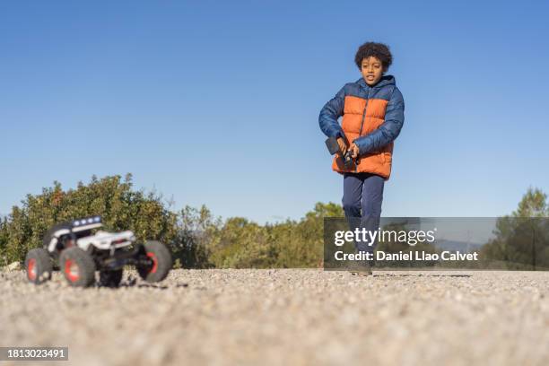 young boy having fun while playing with a remote control car outdoors in nature. - remote control car stock pictures, royalty-free photos & images