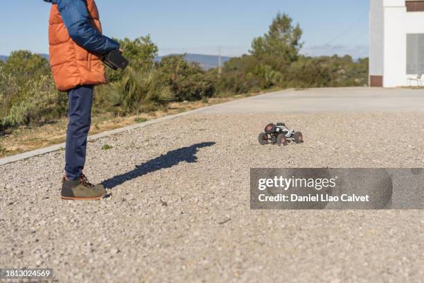 unrecognizable young boy controlling a toy car with a remote control outdoors. - remote control car stock pictures, royalty-free photos & images