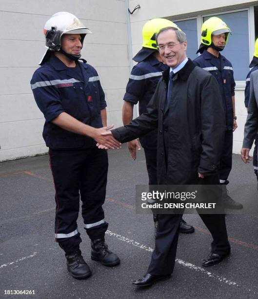 French Interior minister Claude Gueant shakes hands with a French fireman outside a Eurotunnel fire station on June 6, 2011 in the French northern...
