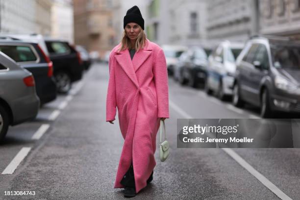 Karin Teigl seen wearing Edited black wool knit beanie, Michael Kors grey wool knit cut-outs top, NA-KD pink oversized long coat, Chanel black denim...