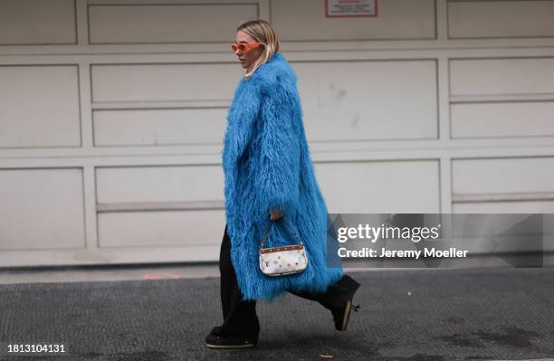 Karin Teigl seen wearing The Attico orange sunglasses, Essential Antwerp blue teddy fur oversized long coat, Zara black striped suit pants, Louis...