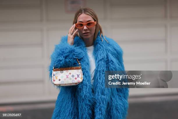 Karin Teigl seen wearing The Attico orange sunglasses, Magda Burtym cream white shirt with flower detail, Essential Antwerp blue teddy fur oversized...