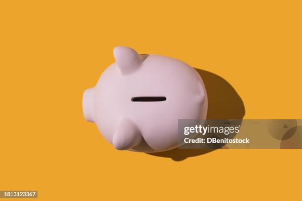 overhead view of pink ceramic piggy bank on yellow background. concept of saving money and savings. - geld und finanzen stock-fotos und bilder