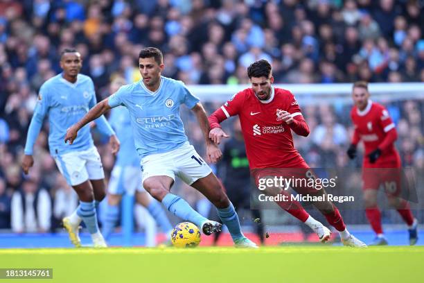 Rodri of Manchester City runs with the ball whilst under pressure from Dominik Szoboszlai of Liverpool during the Premier League match between...