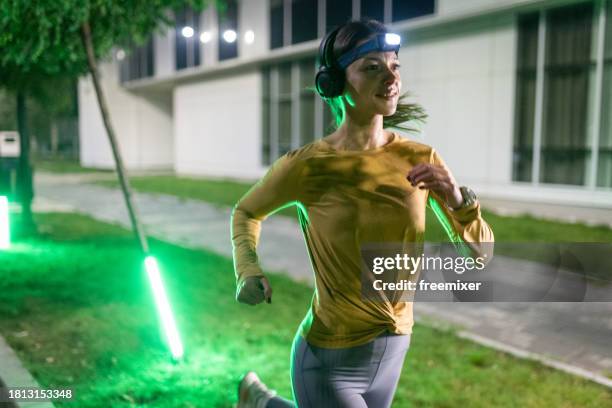 determined woman running in the city at night - wireless headphones stock pictures, royalty-free photos & images