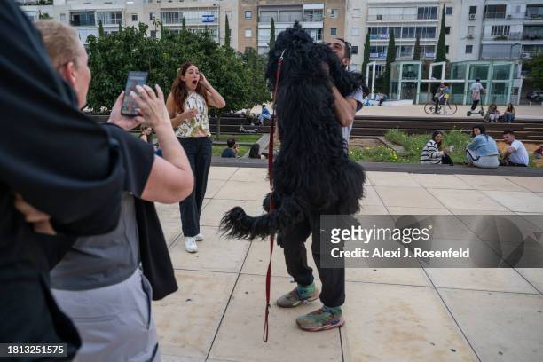 People react to a dog named Steve hugging his owner in Habima Square on November 25, 2023 in Tel Aviv, Israel. A total of 50 hostages currently held...