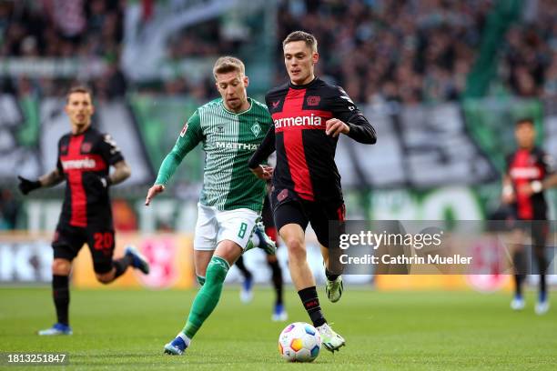 Florian Wirtz of Bayer Leverkusen runs with the ball whilst under pressure from Mitchell Weiser of Werder Bremen during the Bundesliga match between...