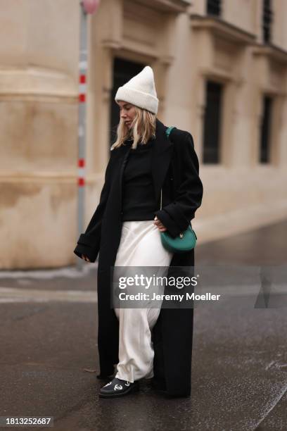 Karin Teigl seen wearing By Aylin Koenig cream white wool knit beanie, Mango cream white satin / silk long skirt, Chanel black wool knit sweater, H&M...