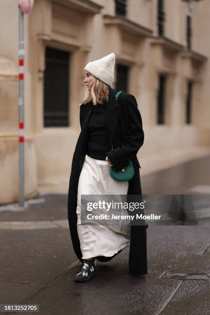 Karin Teigl seen wearing By Aylin Koenig cream white wool knit beanie, Mango cream white satin / silk long skirt, Chanel black wool knit sweater, H&M...