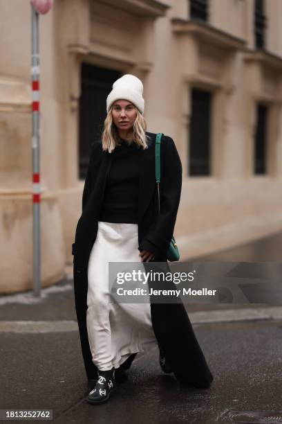 Karin Teigl seen wearing By Aylin Koenig cream white wool knit beanie, Mango cream white satin / silk long skirt, Chanel black wool knit sweater, H&M...