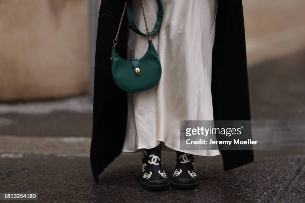 Karin Teigl seen wearing Mango cream white satin / silk long skirt, H&M black wool long coat, Bulgari green leather crossbody bag and Chanel black /...