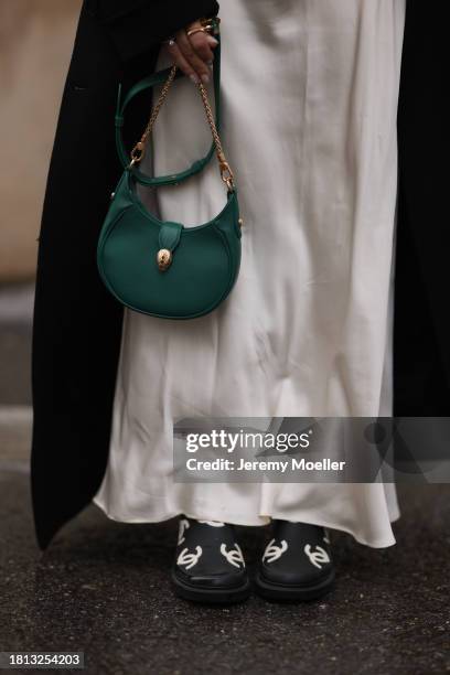 Karin Teigl seen wearing Mango cream white satin / silk long skirt, H&M black wool long coat, Bulgari green leather crossbody bag and Chanel black /...