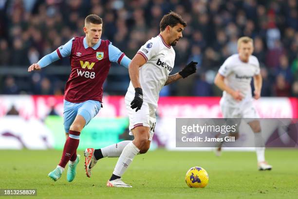 Lucas Paqueta of West Ham United runs with the ball whilst under pressure from Johann Gudmundsson of Burnley during the Premier League match between...