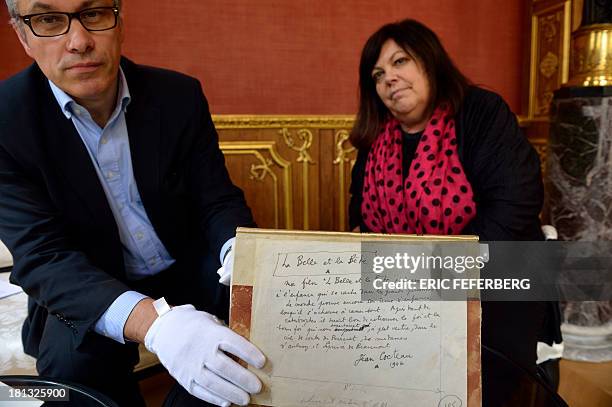 Museum of Letters and Manuscripts administrator Pascal Fulacher and relative of French Artist Jean Cocteau Dominique Marny pose presenting the script...