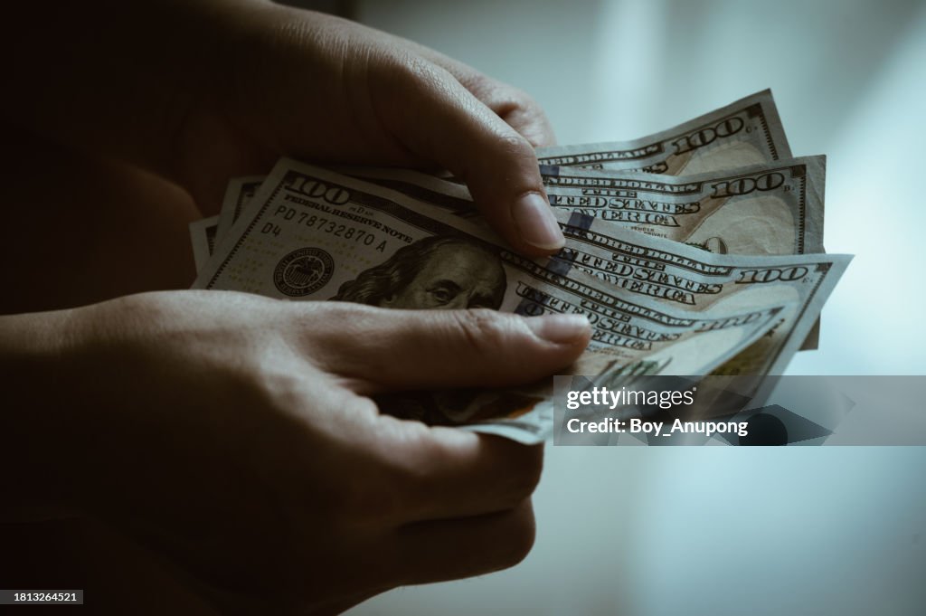 Close up of someone hands holding and counting American dollar banknotes in hands.
