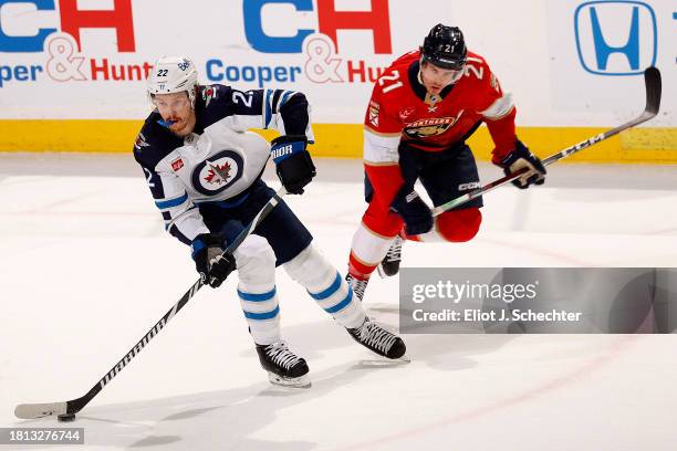 Mason Appleton of the Winnipeg Jets skates with the puck against Nick Cousins of the Florida Panthers at the Amerant Bank Arena on November 24, 2023...