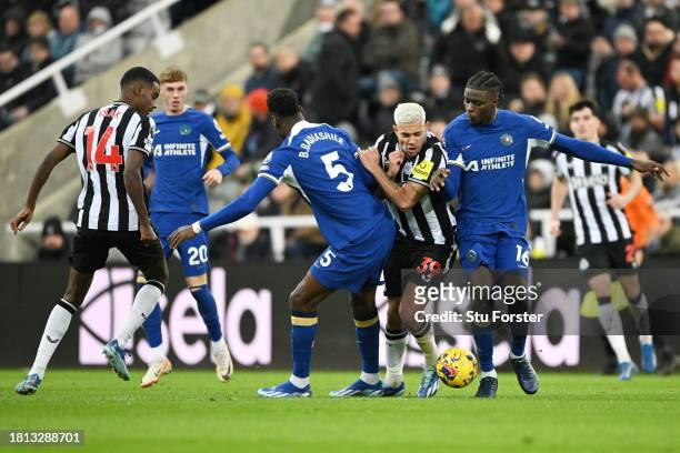 Bruno Guimaraes of Newcastle United is challenged by Benoit Badiashile and Lesley Ugochukwu of Chelsea during the Premier League match between...